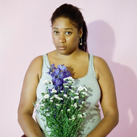 Emma Dennis-Edwards, in a vest, holding flowers and looking serious