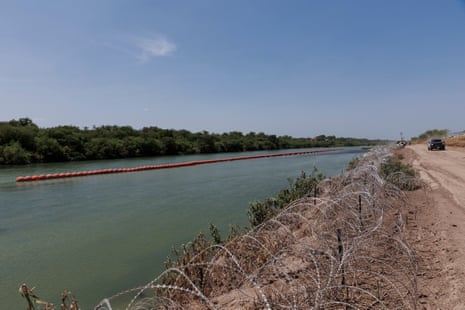 A river with buoys floating in the middle of it.