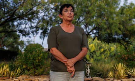 A middle-age woman poses in front of greenery.