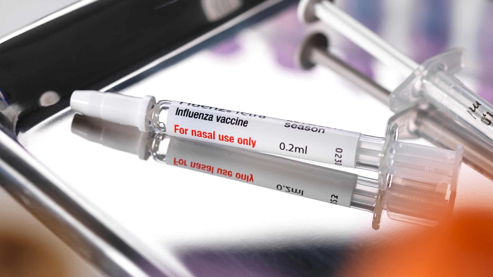 Sealed nasal influenza vaccine laying on a silver medical tray