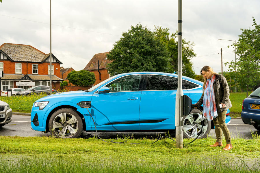 Bright blue Audi E-tron being connected to lamppost electric car charger