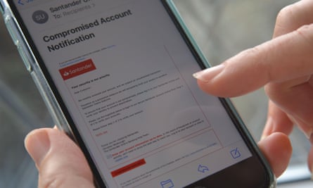 Mobile phone in woman’s hand with a phishing email, purporting to be from the Santander bank, displayed on the screen