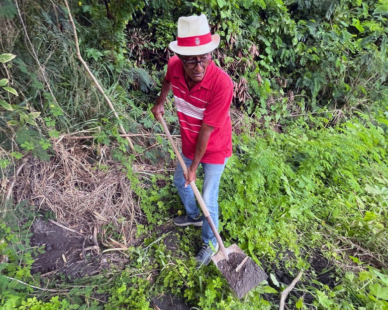 An activist from Guayama digs into the embankment next to a major road as an example of a site where coal ash is visible just inches under the soil.