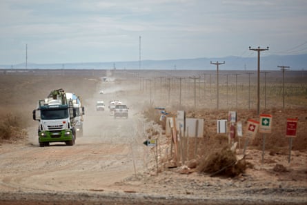 Trucks drive along a dusty road
