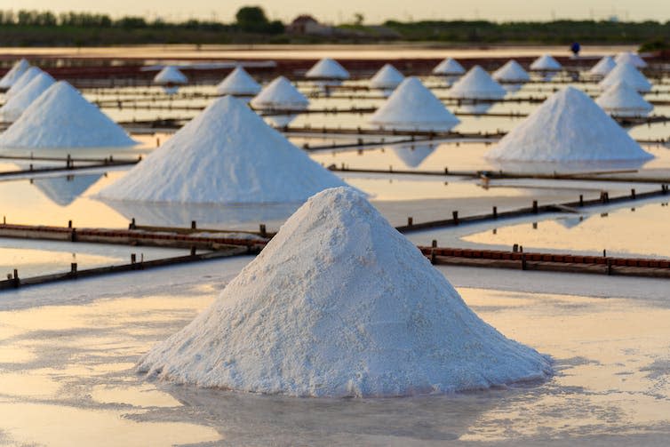 Piles of white sodium in separate brine pools.