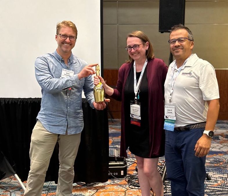 A surprised Prof. Jenn Stroud Rossmann learns of her Olmsted award from LEES Division Chair Sean Ferguson (left) and Juan Lucena.