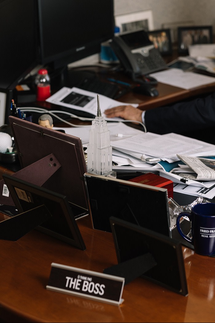 A messy office desk with a plaque that says “The Boss”