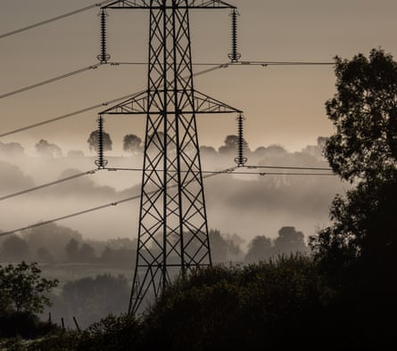 Electrical pylons carry electricity cables across fields still covered in early morning mist near Shepton Mallet, England.