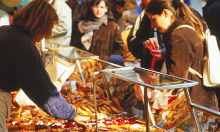 Woman sells tarts to a couple at open market in Bastille