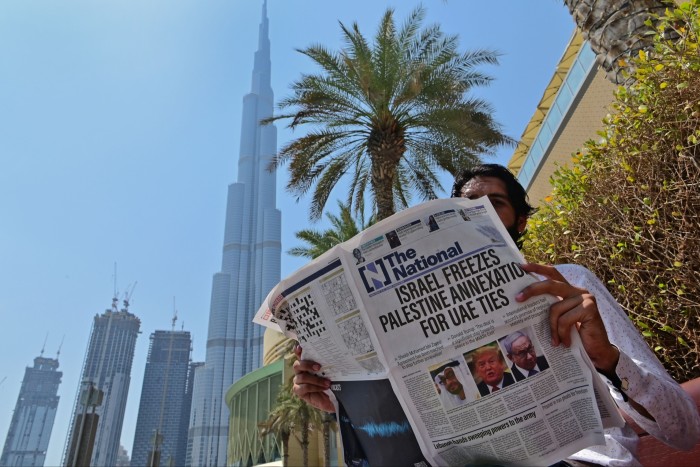 A man reads a copy of UAE-based The National newspaper near the Burj Khalifa