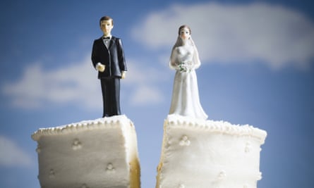 wedding cake being split in half with the bride and groom toppers separated by the cut
