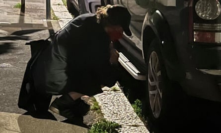 An activist from the Tyre Extinguishers at work in south London lets down an SUV’s tyres on a street at night