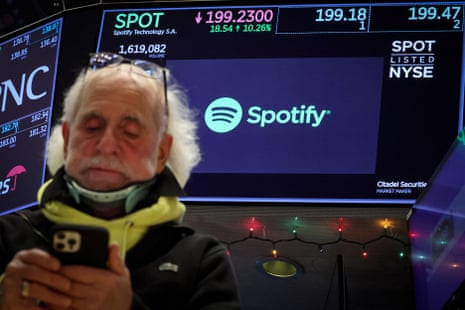 A screen displaying the logo and trading information for Spotify on the New York Stock Exchange, with trader Peter Tuchman in the foreground