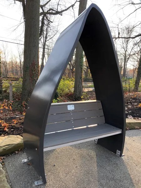 An awning that looks like the hull of a boat sits over a bench made of wind turbine blades.