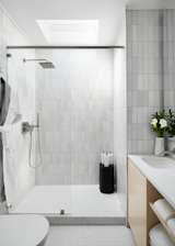 The tiled bathroom has a vanity with open shelving.