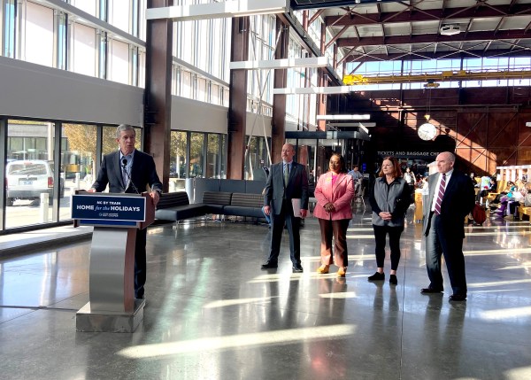 Gov. Roy Cooper stands at a lectern in Raleigh's Union station, flanked by four other people.