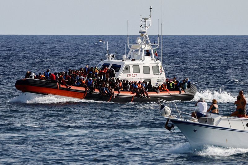 © Reuters. FILE PHOTO: An Italian Coast Guard vessel carrying migrants rescued at sea passes near a tourist boat, on the Sicilian island of Lampedusa, Italy, September 18, 2023. REUTERS/Yara Nardi//File Photo