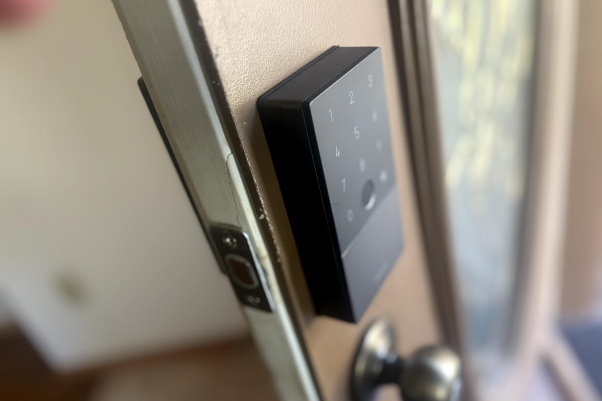 The Aqara U100 lock, showing the keypad on an ajar brown door.