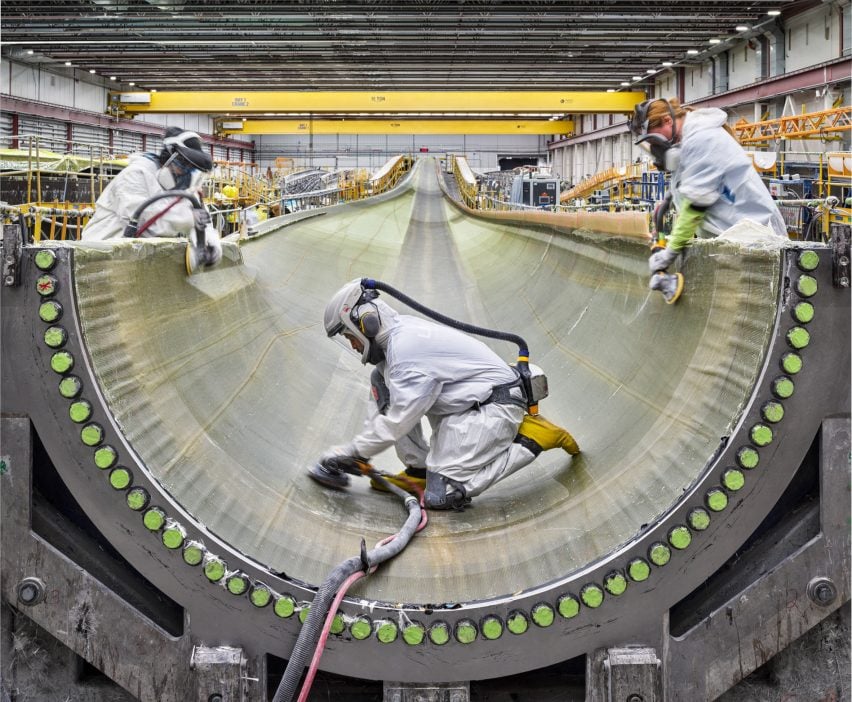 Sanding infused fiberglass inside a wind turbine blade shell.