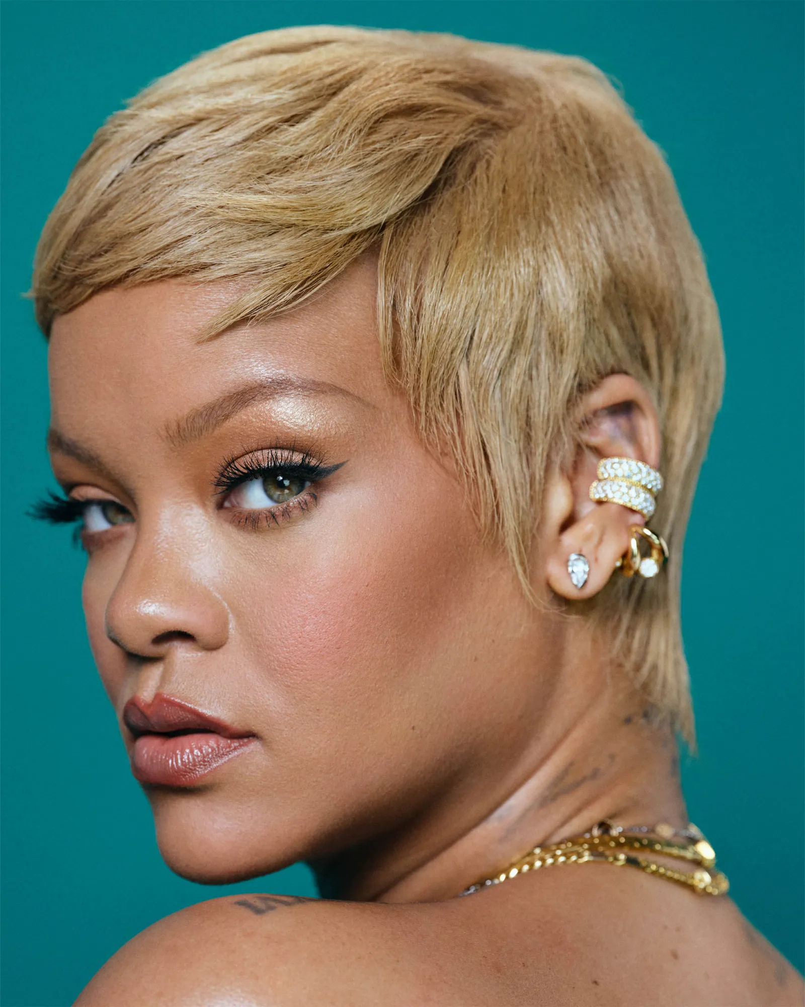 A headshot of a blonde woman on a blue background turning her head toward the camera.