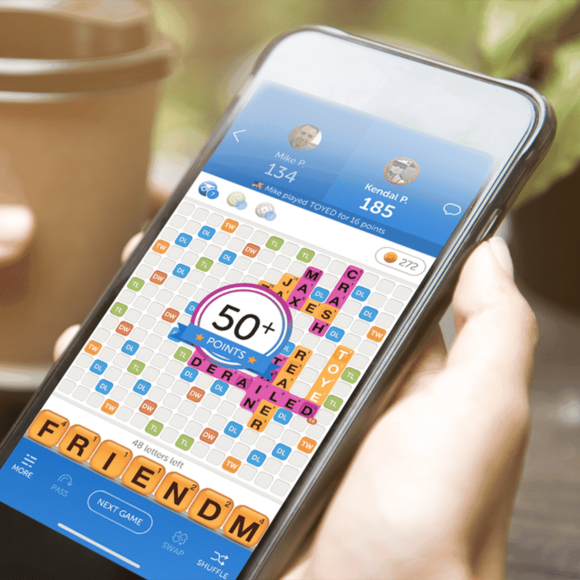 Hand holding mobile device with Words With Friends 2.