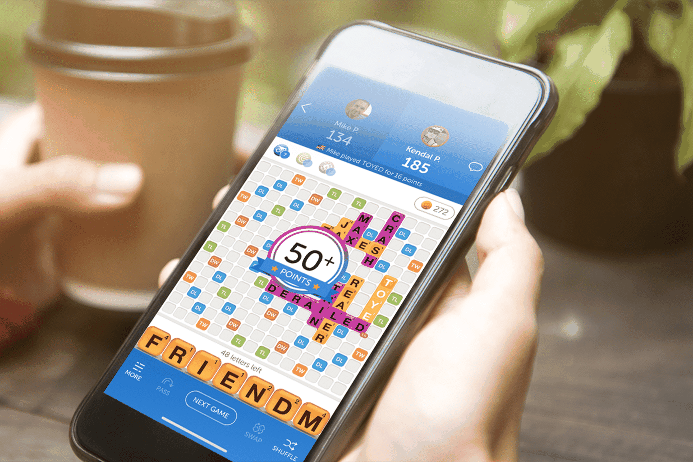 Hand holding mobile device with Words With Friends 2.