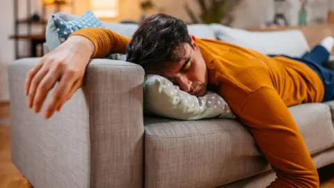 Getty Images A man asleep on the sofa