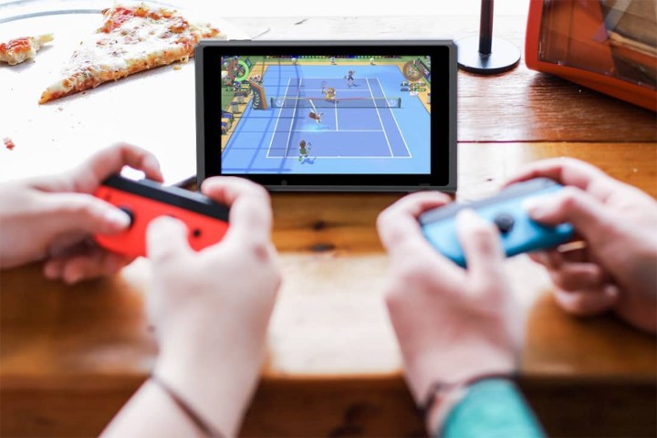 Two people playing a Nintendo Switch that is propped up on a table.