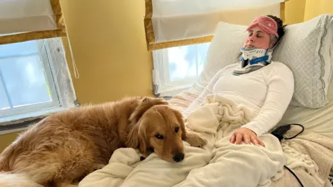 John McGinty Georgia McGinty in a hospital bed in a neck brace, with her dog lying next to her