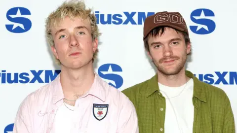 Getty Images The two band members of Good Neighbours. Oli has short blonde hair and Scott has short brown hair. 