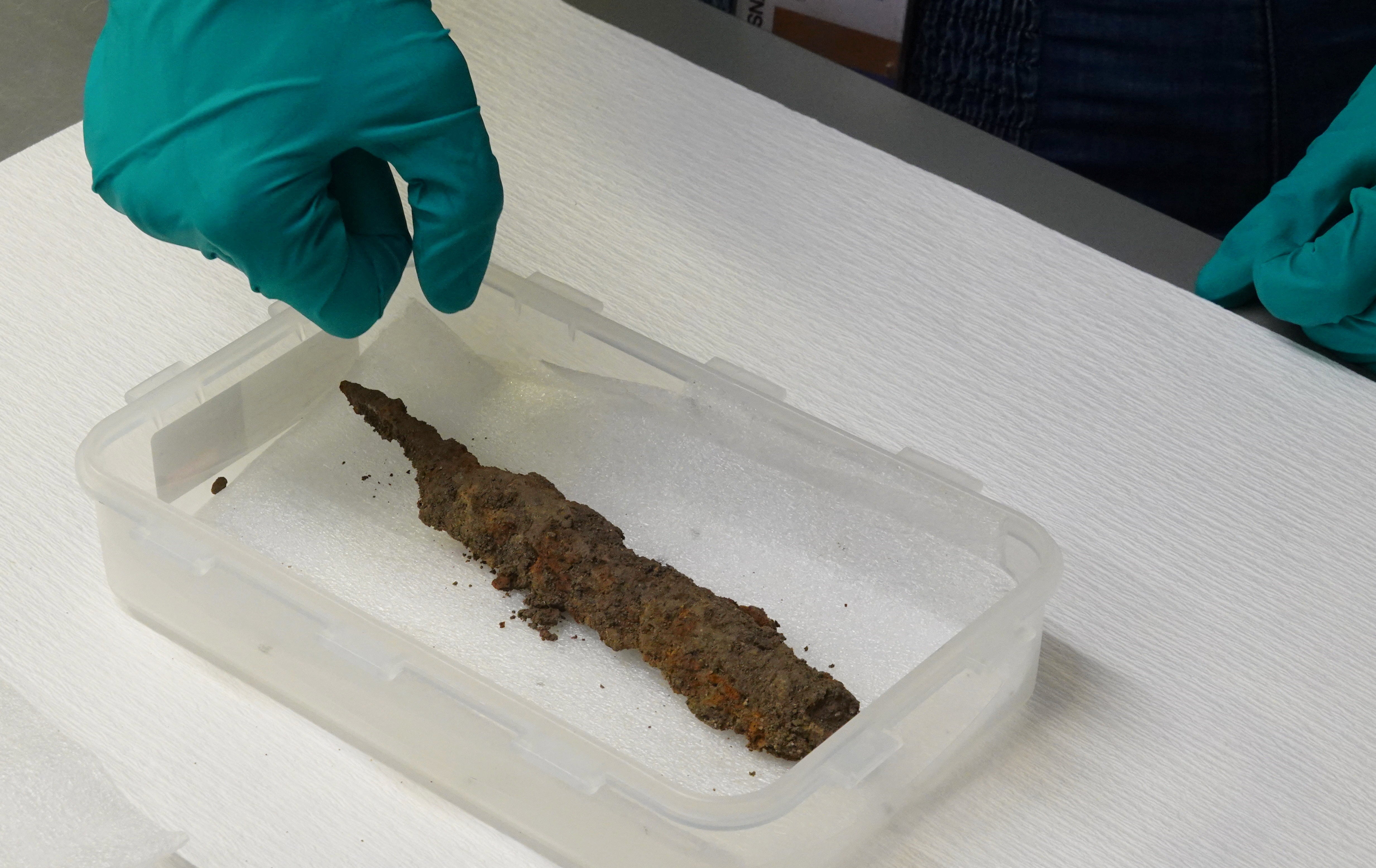 A conservator displays an iron knife found in a Viking-age burial site in excavations at the village of Aasum during an interview in a laboratory at Museum Odense, Denmark