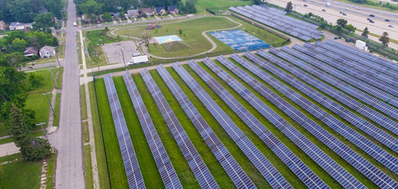 A large solar array in Detroit surrounded by homes, a city park, and a freeway.