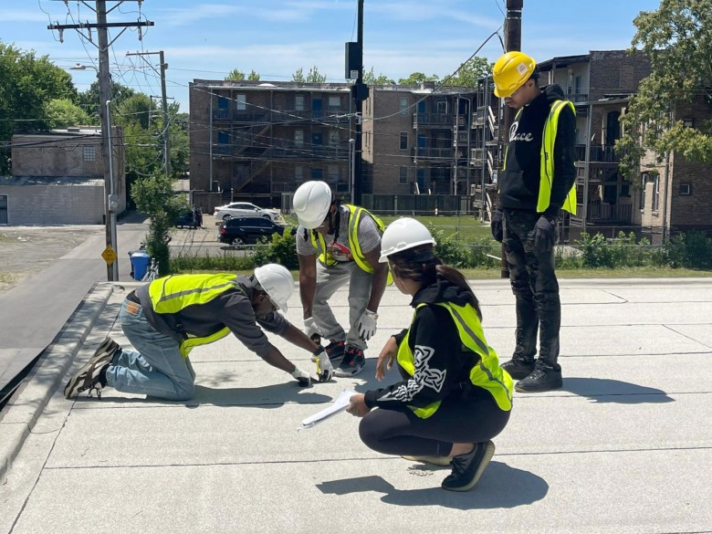 Solar trainees in vests and hard hats on a rooftop.