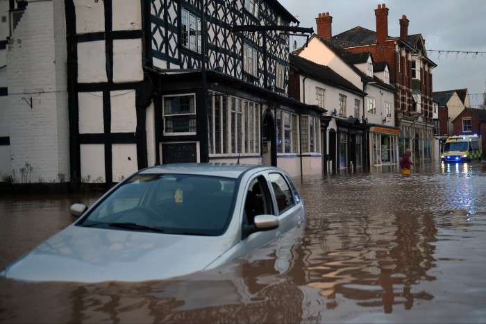 Flood water surrounds abandoned cars left in a flooded street in Tenbury Wells in 2020, after Storm Dennis 