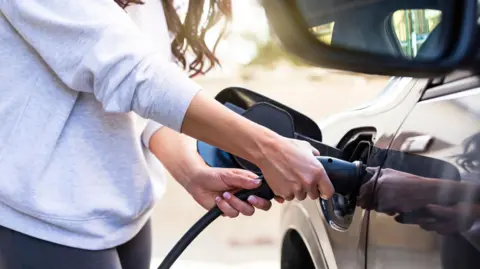 Getty Images Woman charging electric car at station 