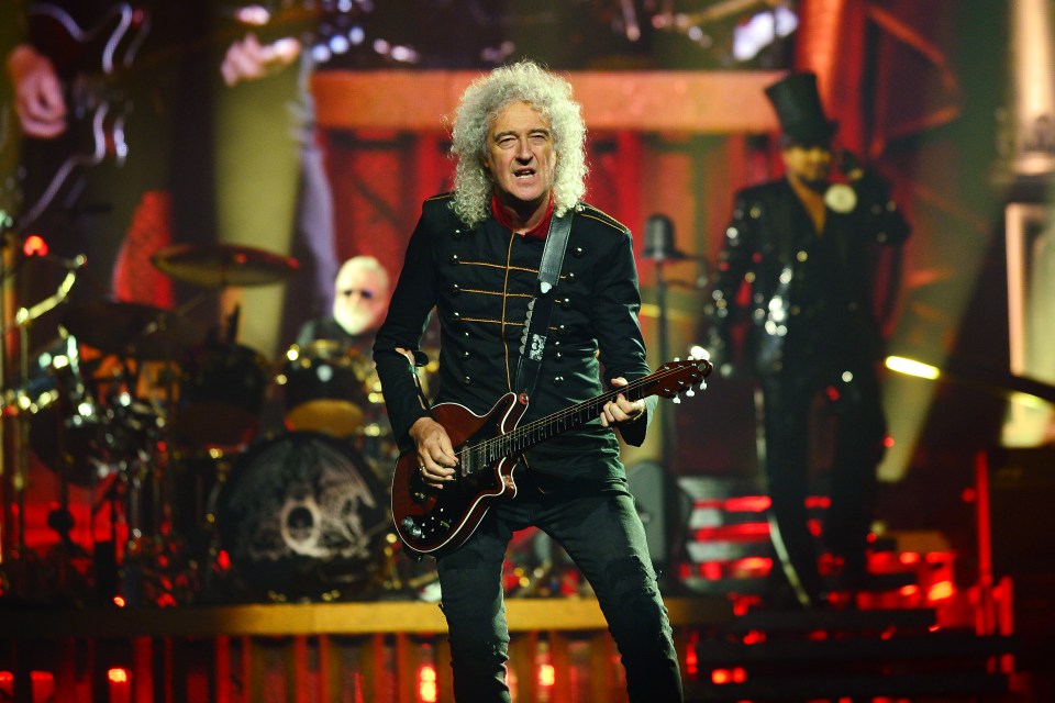 Brian May of Queen performing on stage.