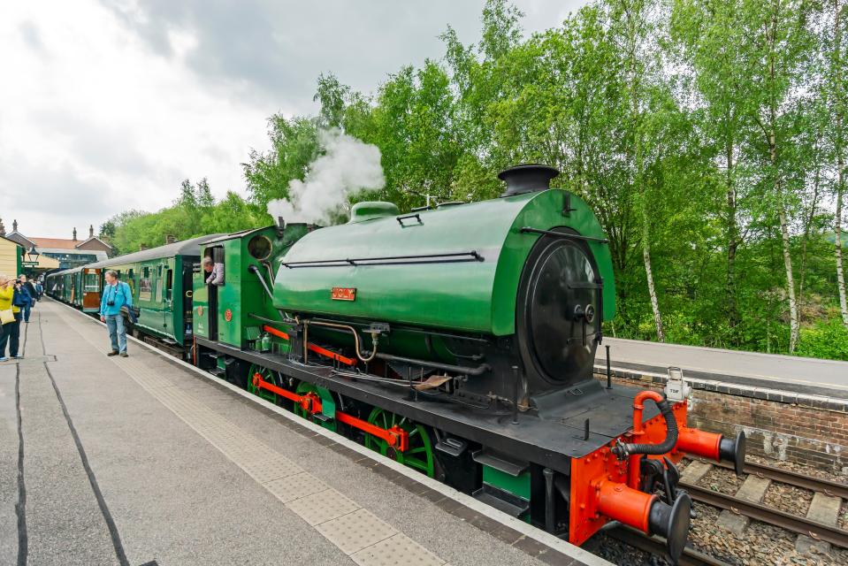 Green steam train at a station.