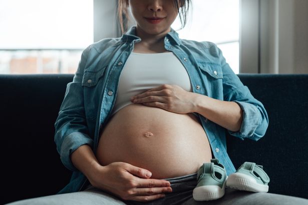 Midsection of pregnant woman embracing her belly. Pregnancy healthcare and wellbeing.