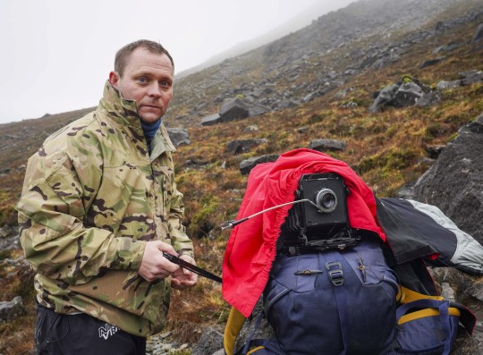 Photographer Simon Riddell, 41, who is scaling the Cuillin Mountain on Skye to take incredible Victorian-style photographs. See SWNS story SWNAphoto. A photographer is scaling a mountain to take incredible Victorian style pictures using a rare process - invented nearly 200 years ago. Simon Riddell, 41, took up wet plate collodion in 2020 to help with his mental health and said the complicated process is used by just a handful of people around the world. Invented in 1851, it sees photographic material, usually glass or aluminium coated in collodion, sensitised in a silver nitrate bath, and developed within ten minutes.