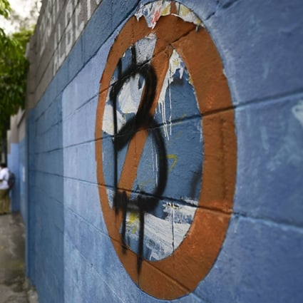 Students walk past a wall painted with an anti-bitcoin protest symbol in San Salvador, El Salvador, on October 18, 2022. The boom and bust in cryptocurrency markets in the past three years has sparked fears among regulators and efforts to rein in digital currencies and their associated technology. Photo: AFP