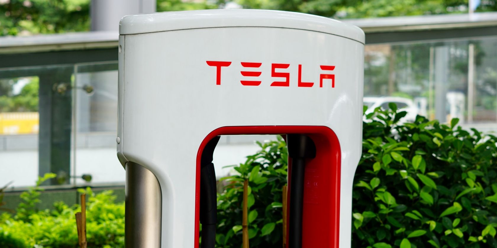 red and white tesla supercharger near bushes