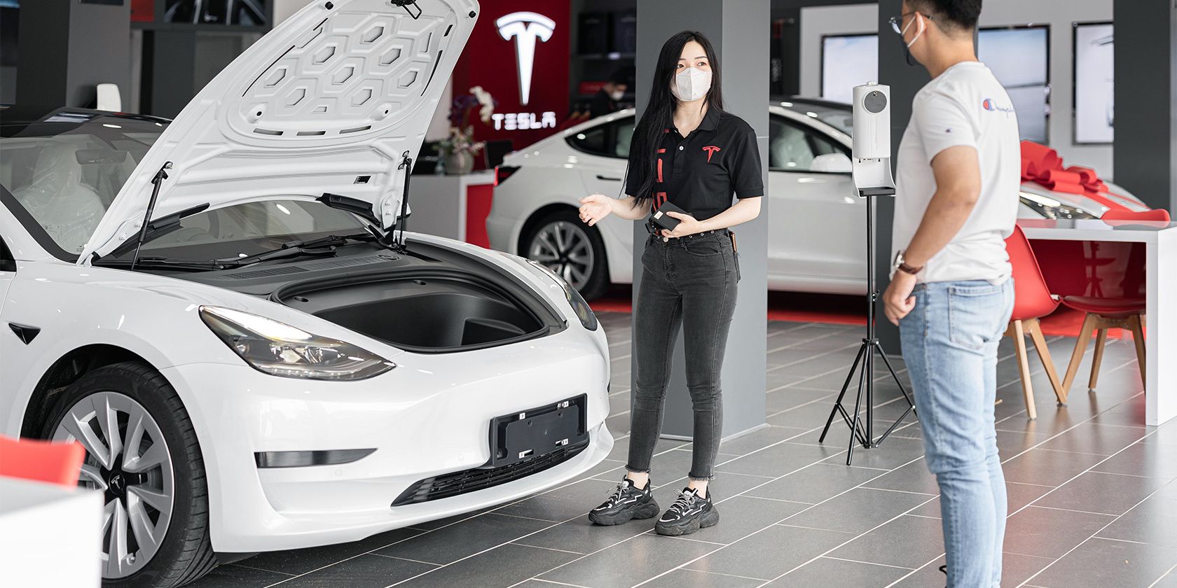 Person Looking at a Tesla Model 3 in a dealership.