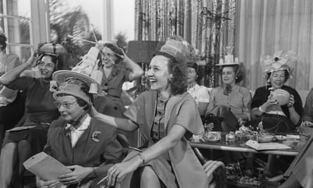 Black and white photo of woman in a lounge room with Tupperware bowls on their heads as hats