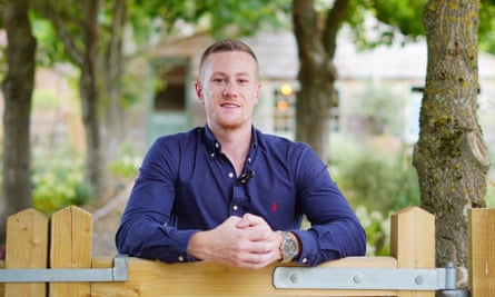 Publicity photograph of Jack Mason in a blue shirt leaning on a suburban wooden garden gate 