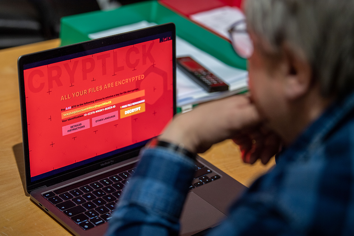  man sits in front of a laptop infected with ransomware. In attacks with extortion software, data on computers is encrypted and the hackers demand money for its release. Photo by Lino Mirgeler/picture alliance via Getty Images.