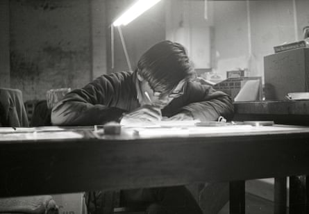 Black and white picture of a man crouched over a desk