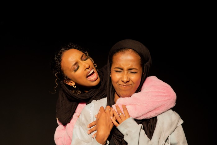 Two schoolgirls laugh while hugging