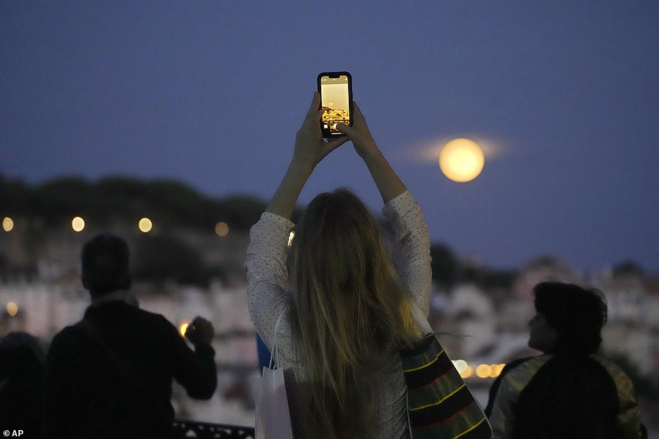 LISBON: A woman takes pictures of a supermoon rising above Lisbon