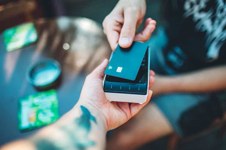 Adult man paying with credit card at cafe, close-up of hands with credit card and credit card reader