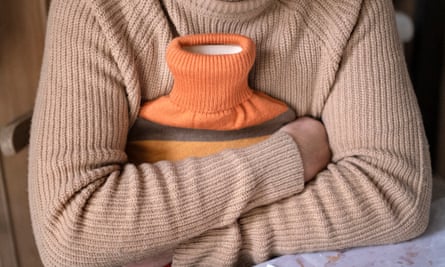 A man in a jumper holds a hot-water bottle